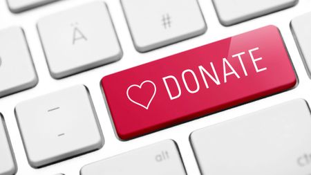 Red donate key with a white heart on a white keyboard