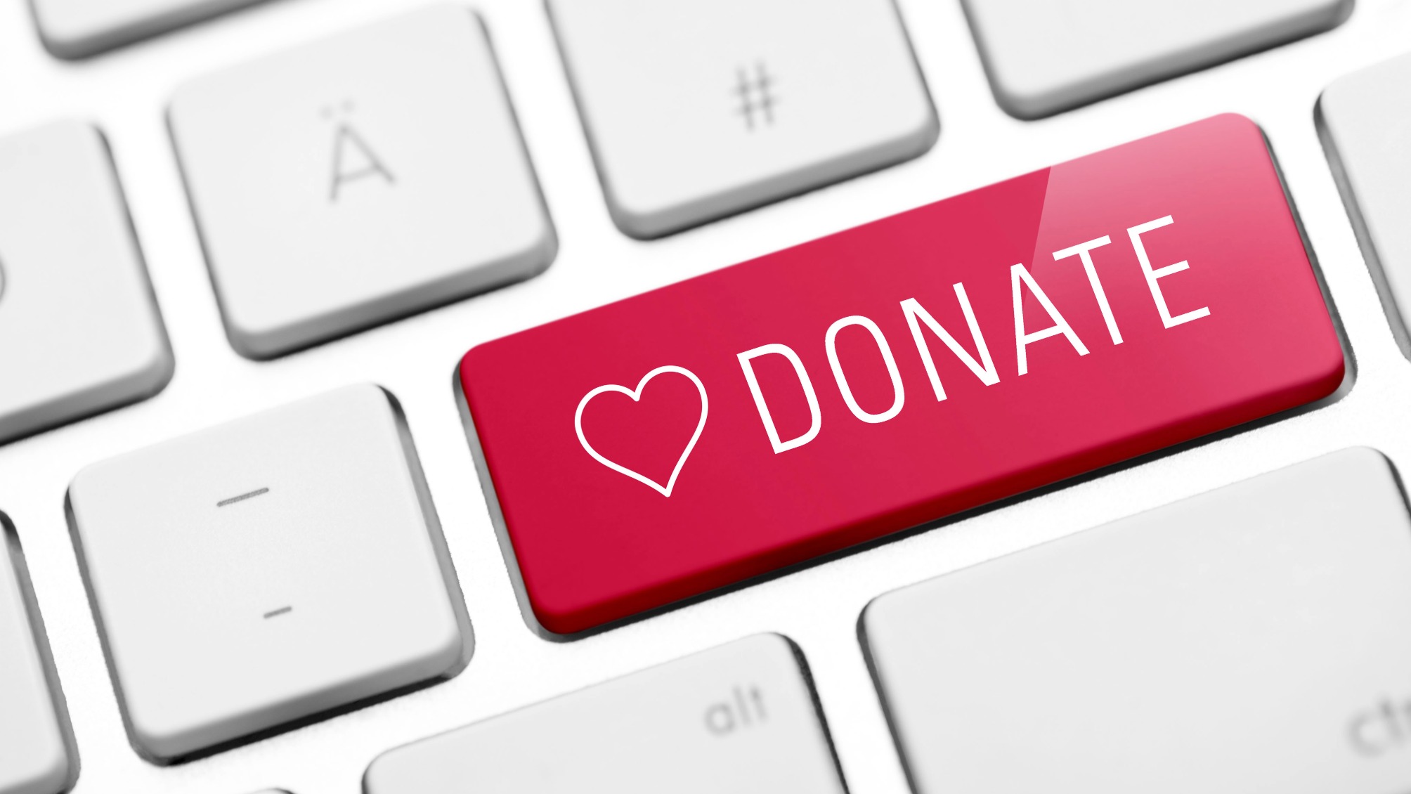 Red donate key with a white heart on a white keyboard