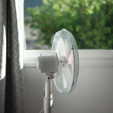 Standing fan pointing out of a window