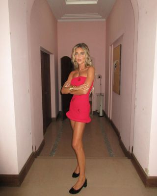 Emili Sindlev wears a red strapless minidress with black ballet pumps.