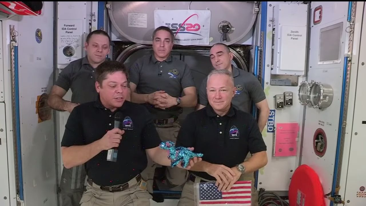 Demo-2 astronauts Bob Behnken and Doug Hurley (bottom row from left) show off their "zero-g" indicator, a dinosaur named Tremor, during a farewell ceremony at the International Space Station, on Aug. 1, 2020.
