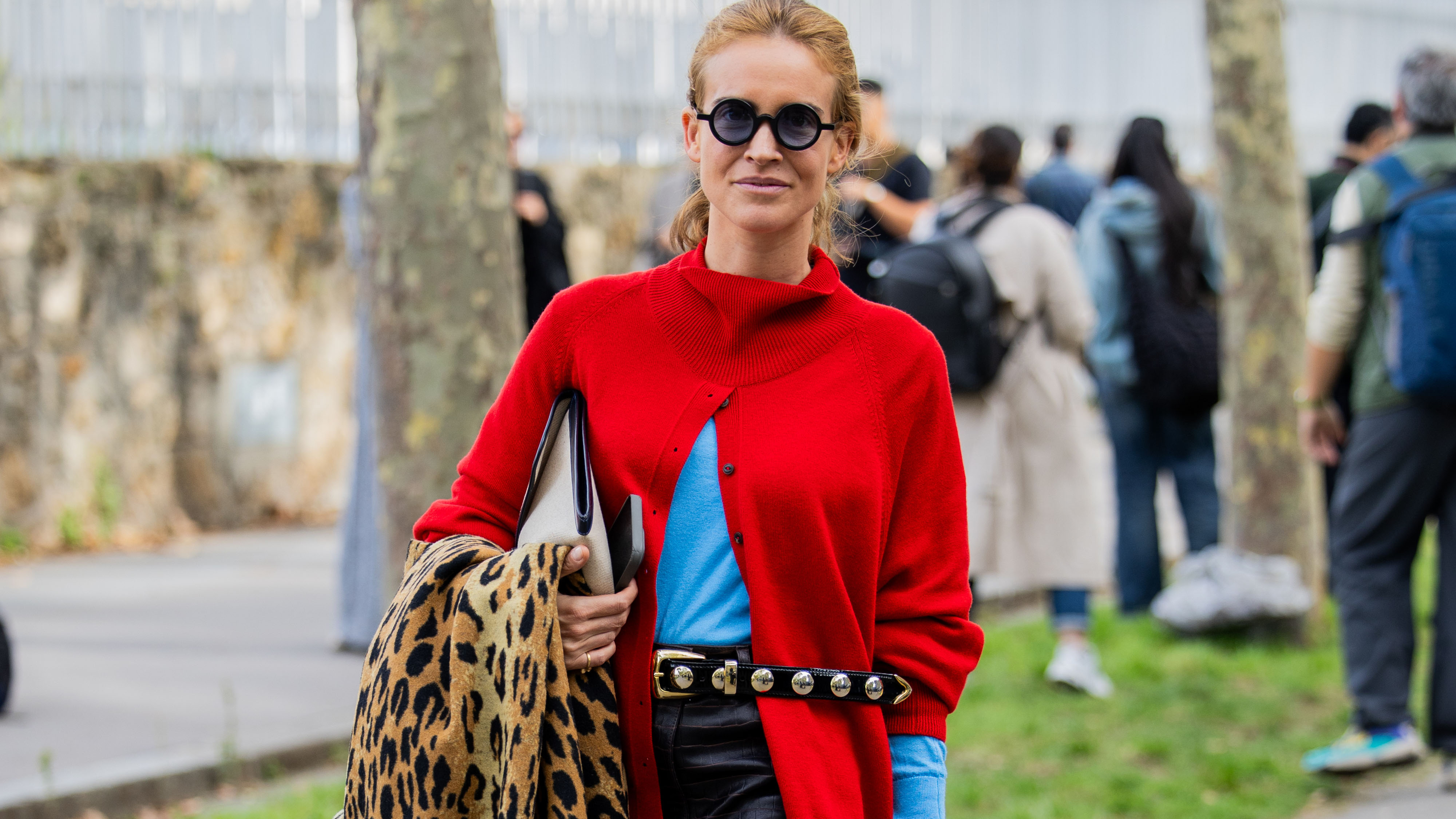 Woman in a red sweater carrying a leopard print coat