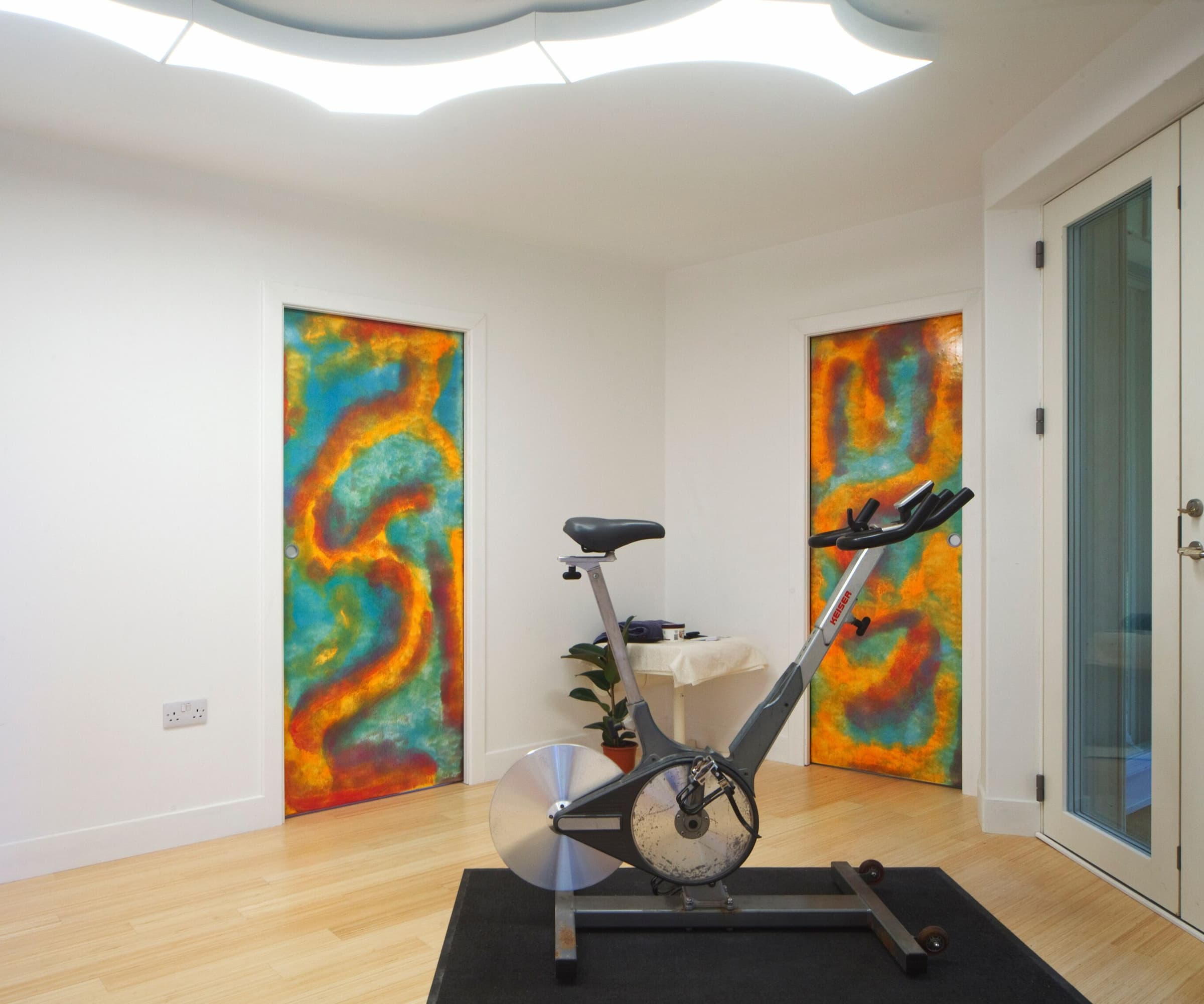 A gym with a cycling machine and overhead lights