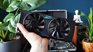 EVGA version of Nvidia GeForce GTX 970 being held with plants in bakcdrop