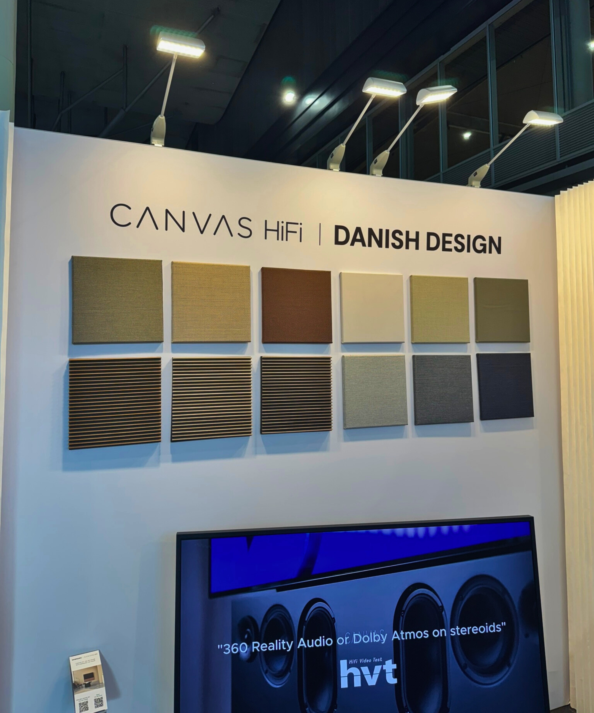 Panel of various 'CANVAS HiFi' designs on white wall, above TV screen, displayed at ISE Barcelona 2026.