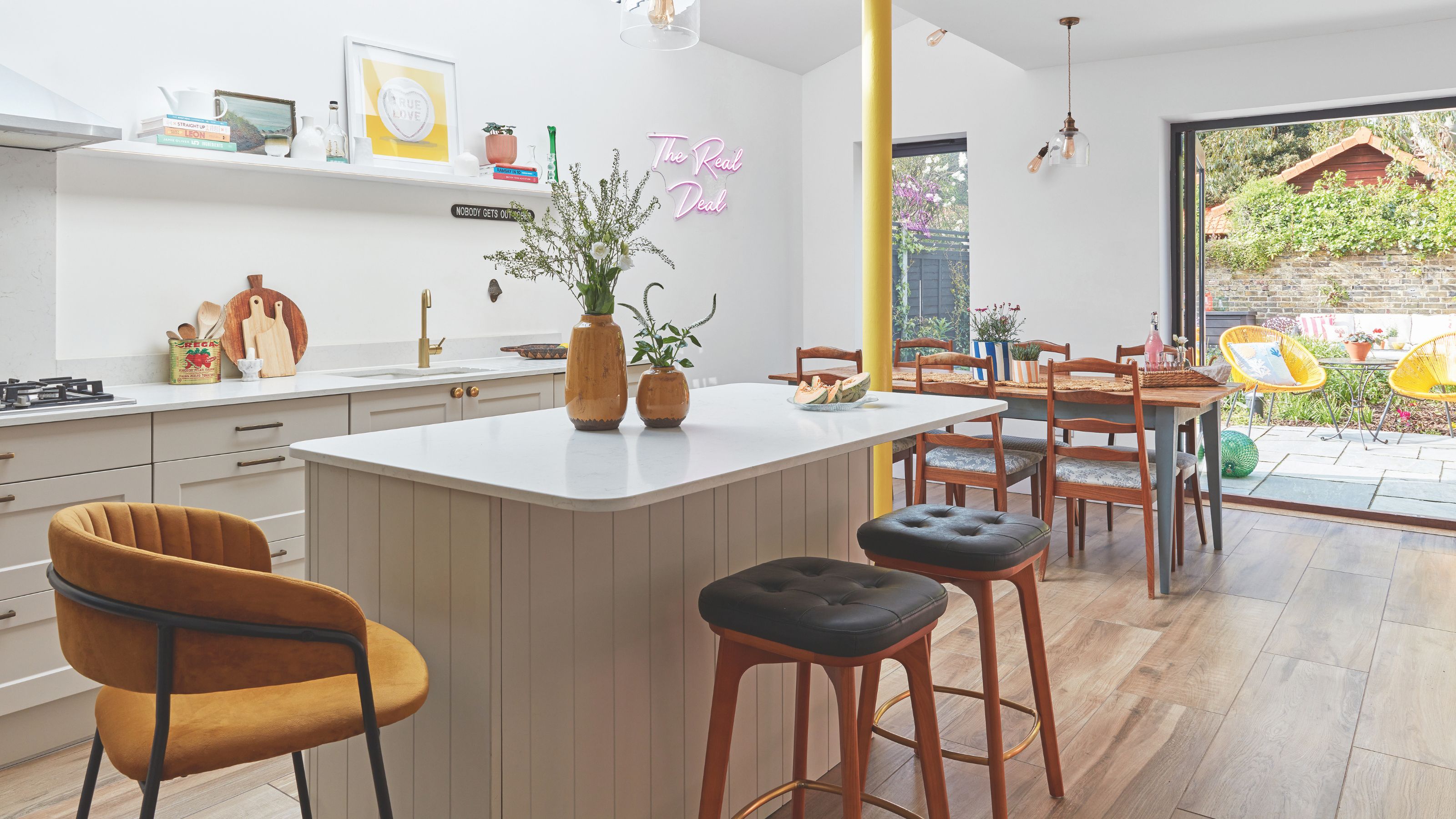 Open plan kitchen and dining area with a kitchen island and bar stools with a dining table beyond