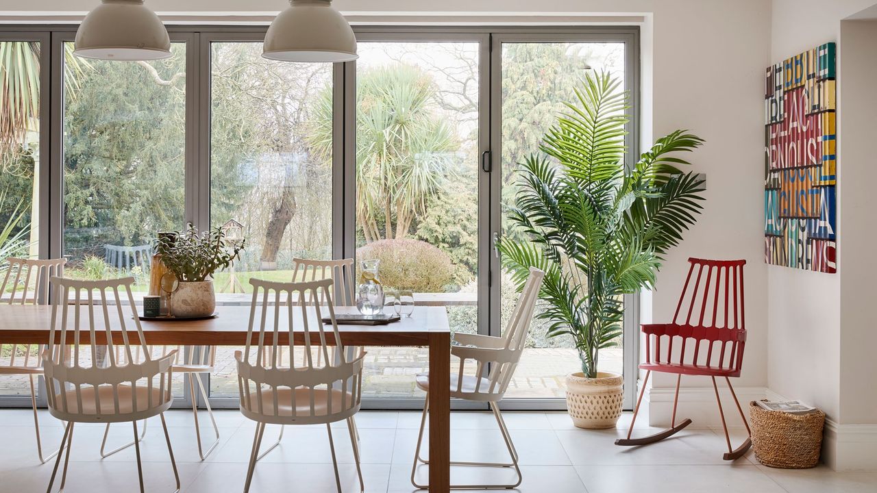 open plan dining area with hanging lights and glass stacked doors and wooden table with white chairs