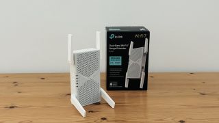 TP-Link BE6300 Wi-Fi extender on wooden desk