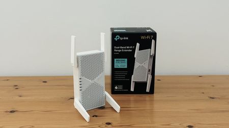 TP-Link BE6300 Wi-Fi extender on wooden desk