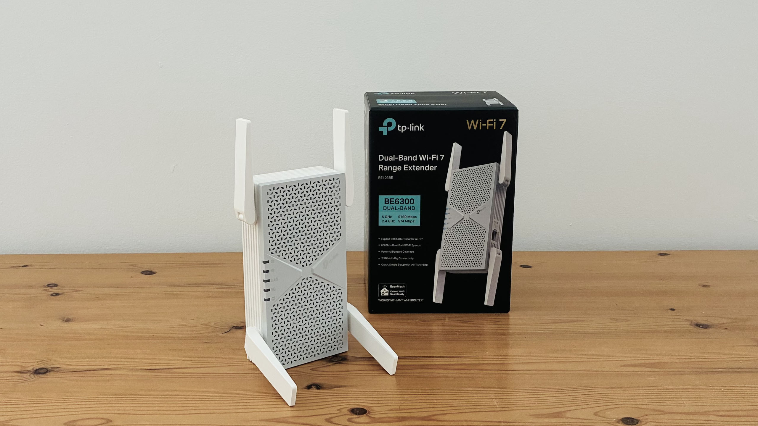 TP-Link BE6300 Wi-Fi extender on wooden desk