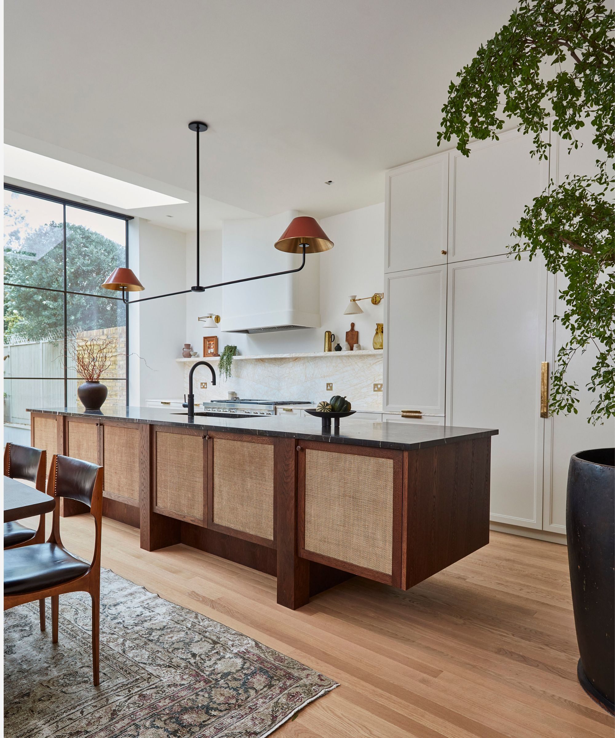 An open kitchen-diner with a dark wooden kitchen island with rattan cupboard doors