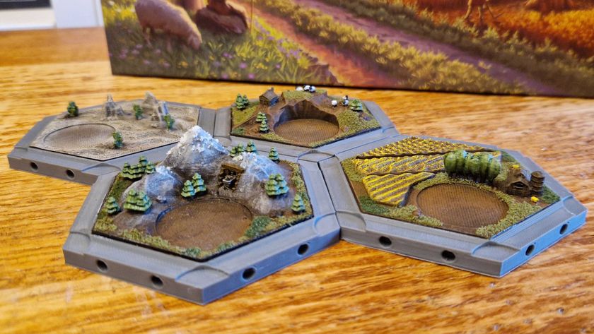 Four 3D, painted Catan tiles sitting together on a wooden table, with the Catan box visible in the background