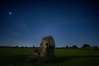 Stars in the night sky over a stone in the landscape