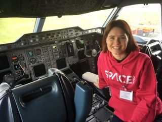 a woman in a red space.com hoodie in the cockpit of an aircraft