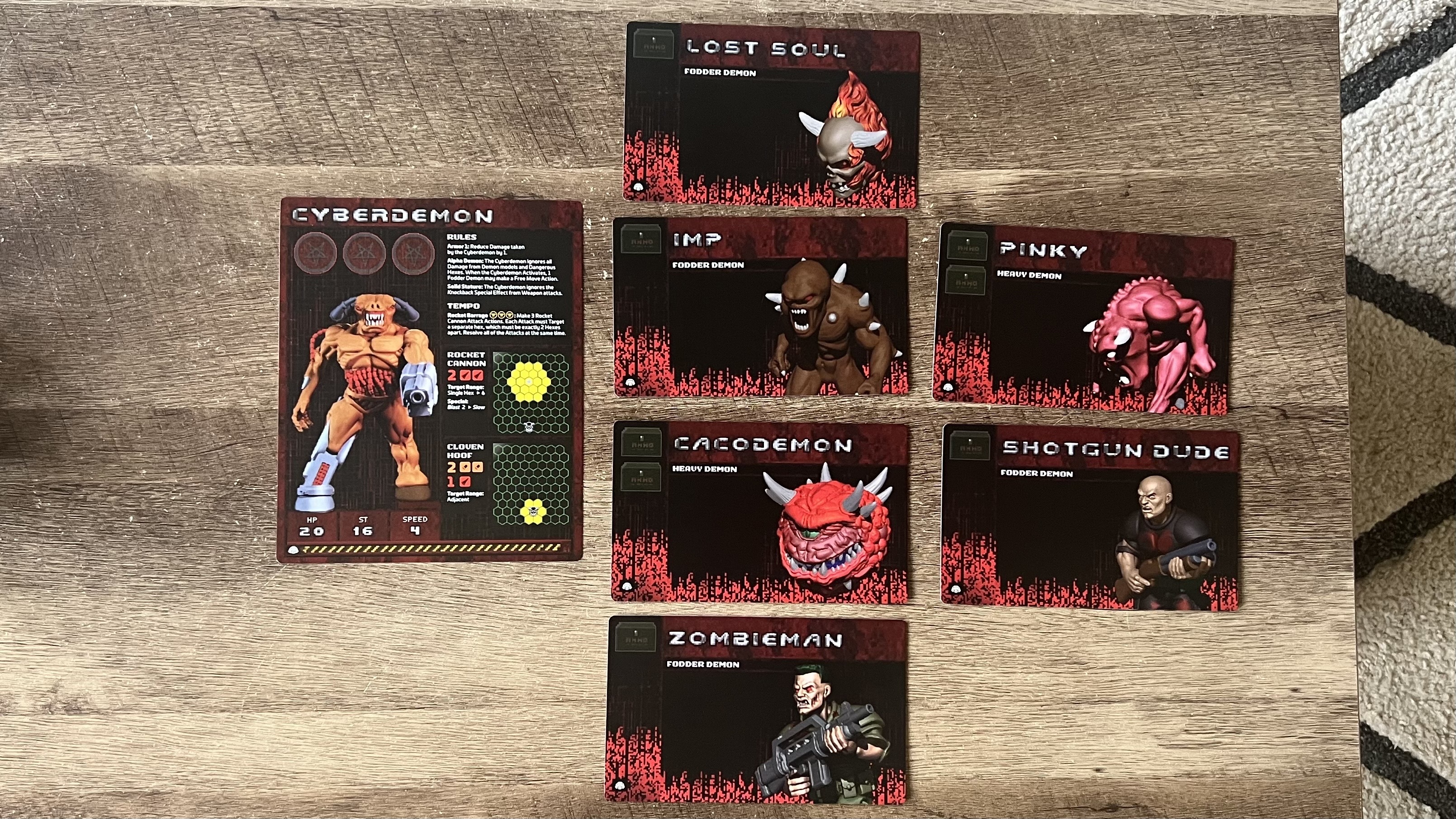 All demon cards from Doom Arena Board Game laid out on a wooden table