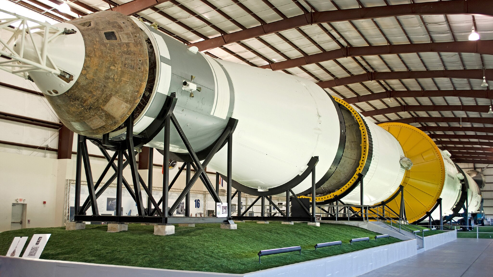 A large white rocket is held up by metal struts for display.