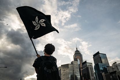 A protester waves a blackened flag of Hong Kong.