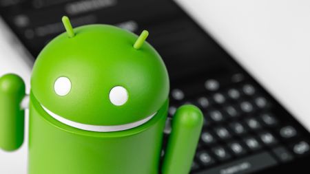 Google Android figure and smartphone with keyboard closeup. 