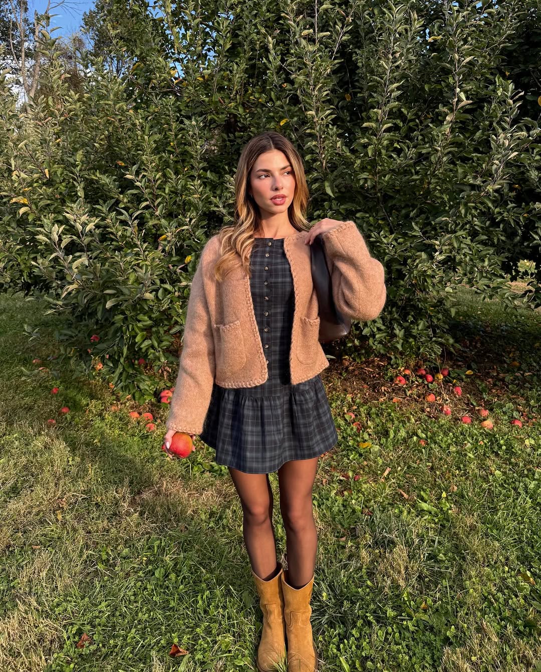 Kit Kennan poses in an apple orchard with glossy blonde hair