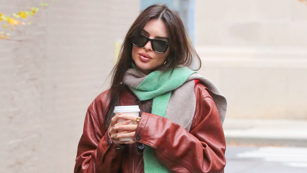 Emily Ratajkowski walking in new york city wearing a leather jacket and carrying a coffee