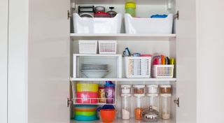 Open kitchen cupboard with plastic containers on shelves for organization
