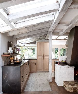 A rustic modern kitchen with beamed ceilings and skylights, and a wooden floor