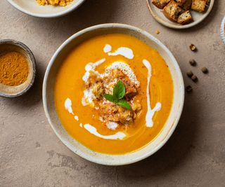 carrot soup in a bowl with creme fraiche and crutons on top