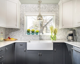 Kitchen with blue floor cabinets, white wall cabinets and grey zigzag pattern backsplash