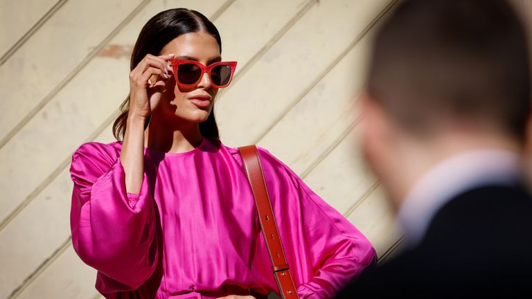woman standing in the sun wearing a pink dress and sunglasses