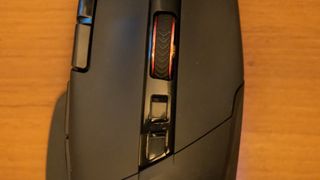 A black AOC AGM600 gaming mouse sitting on a brown wooden desk