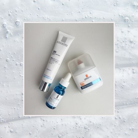 three la roche posay products including a sunscreen, serum, and dark spot treatment on a background of bubbly skincare products