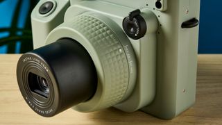 A sage green Fujifilm Instax Wide 400 instant camera