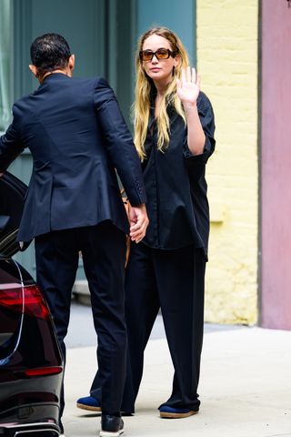 jennifer lawrence wears a black button-up and matching trousers.