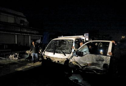 A man pushes his damaged car away from the site of a car bomb attack in New Baghdad. 