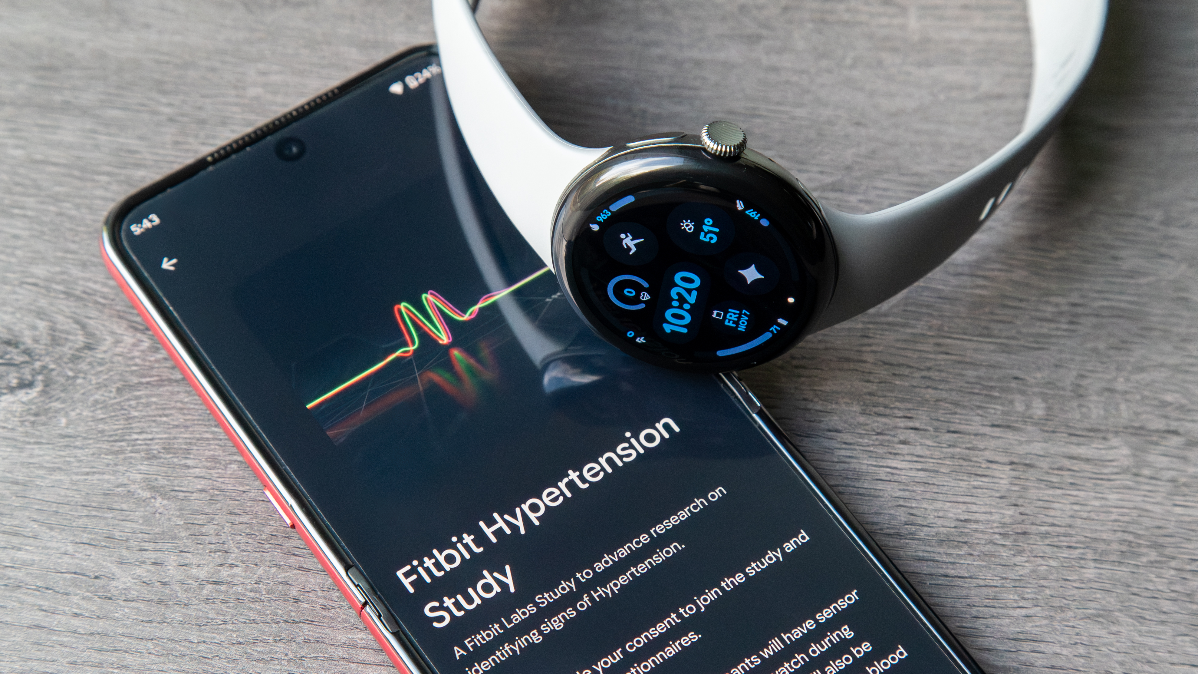 A photo of the Google Pixel Watch 3 sitting atop an Android phone showing a &quot;Fitbit Hypertension Study&quot; from Fitbit Labs.