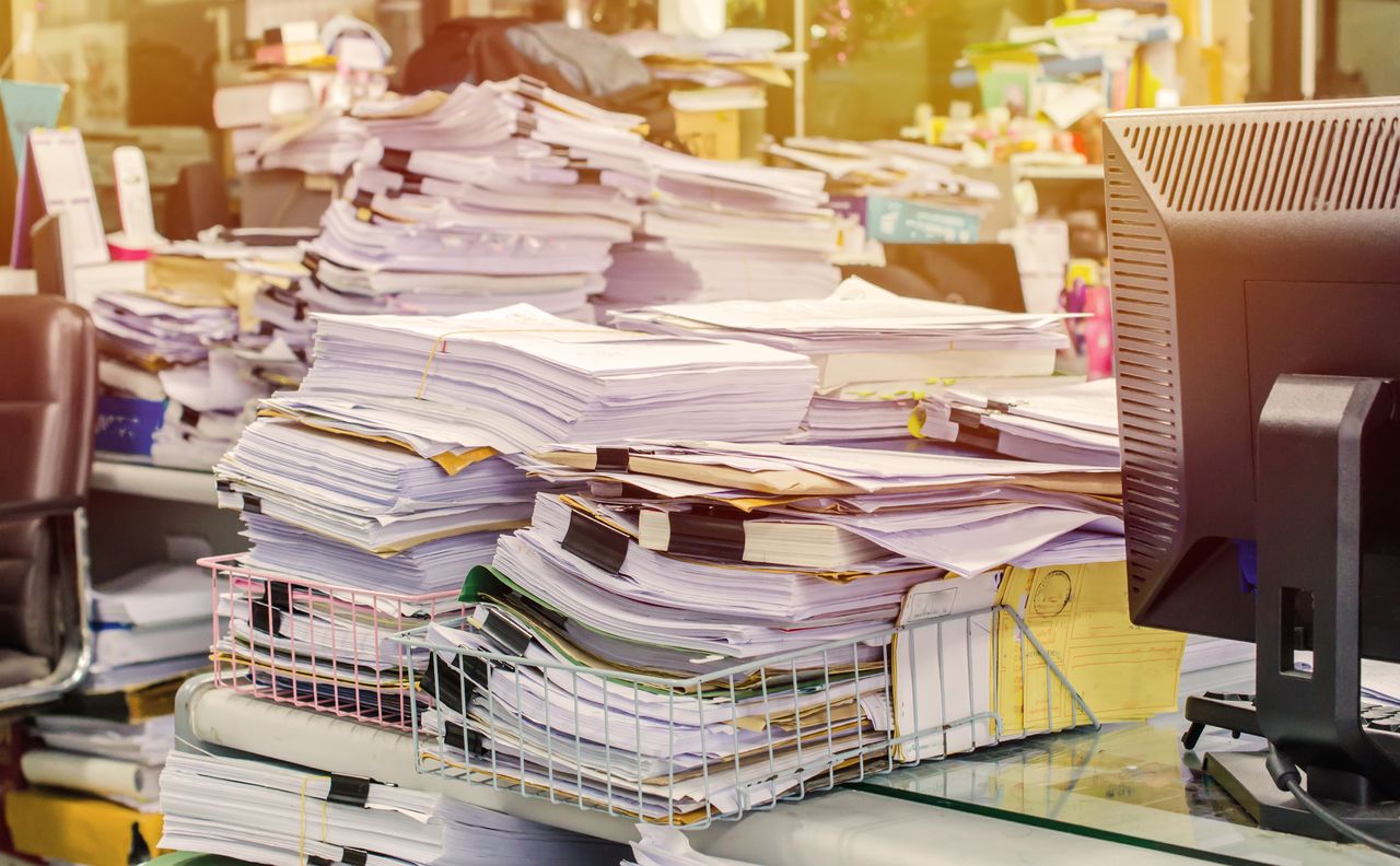 Stacks of papers on desk.