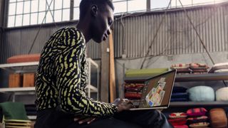 En ung kvinna sitter och arbetar på en Apple MacBook Air 2024.