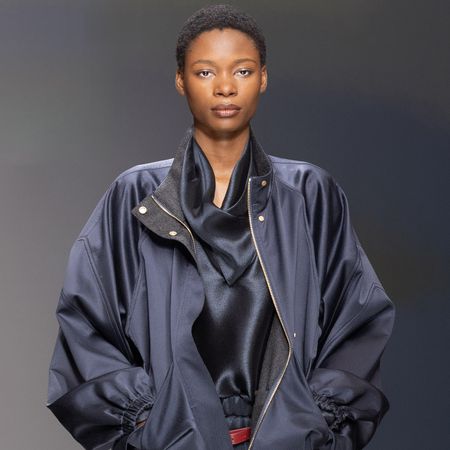 a model wears a blue jacket and blue silk blouse.