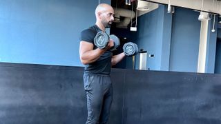 a photo of trainer Ali Malik performing a dumbbell bicep curl