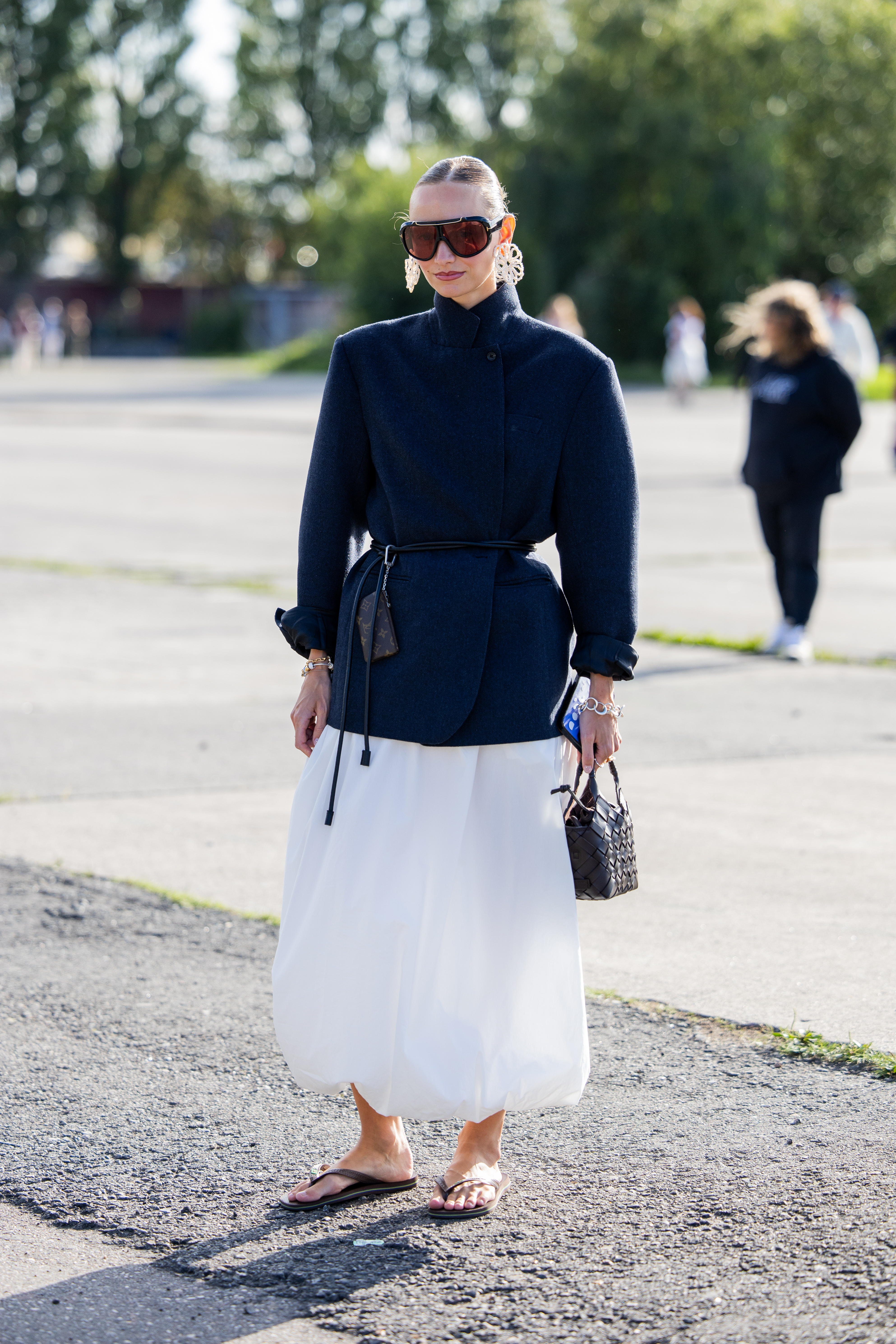 a guest at copenhagen fashion week wearing flip flops with a skirt and a parka
