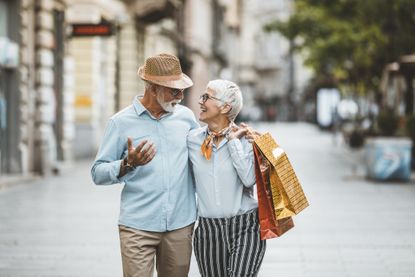Senior Couple, Casually Dressed, is Walking in the City Center with Shopping Bags.