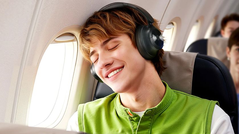 A mean wearing the OneOdio Focus A1 Pro headphones on an airplane. He's leaning his head against the window, with his eyes closed and a smile on his face, implying that the headphones are distracting him