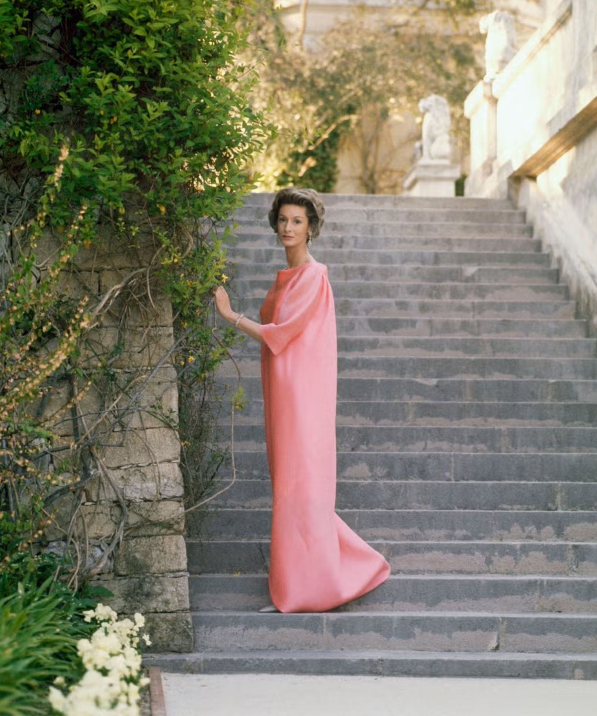Marella Agnelli in pink dress standing on an outdoor staircase