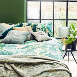 green walled bedroom with floral bed and cushions