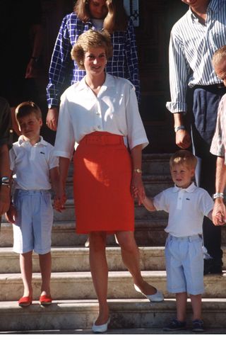 Princess Diana wears a white shirt and a red pencil skirt for a photocall in Majorca with son, Prince William and Prince Harry