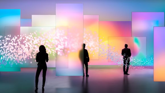 Three people stand in front of multicolor displays from Sony. 