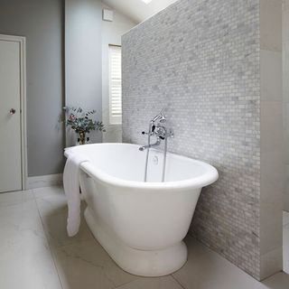 bathroom with bathtub and towel with pale grey marble floor