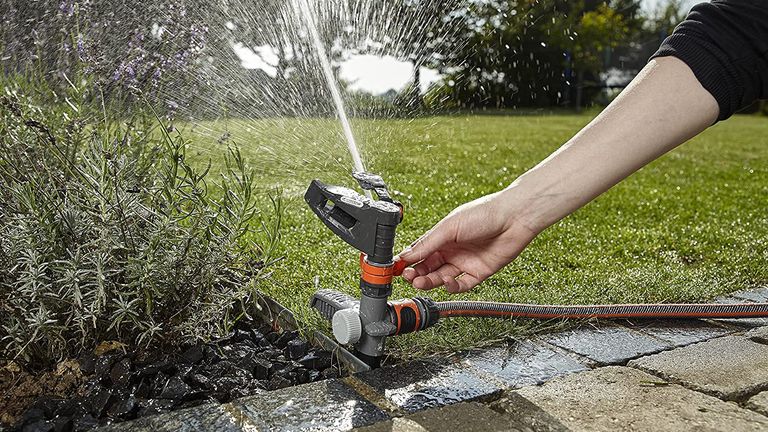 Gardena Comfort Pulse garden sprinkler being setup to water a flowerbed and lawn