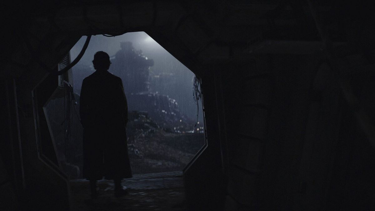 A silhouette of a man is standing in a dark opening.
