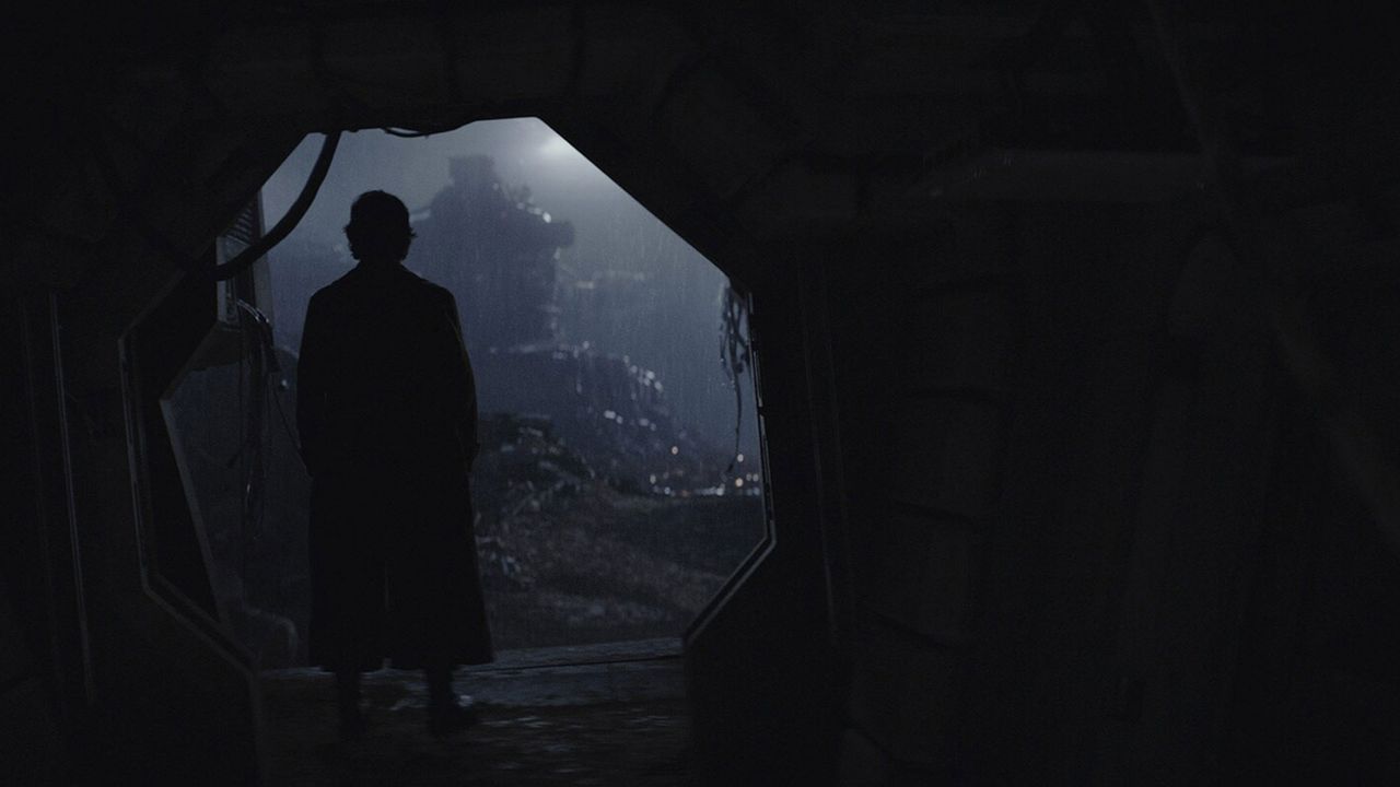 A silhouette of a man is standing in a dark opening.